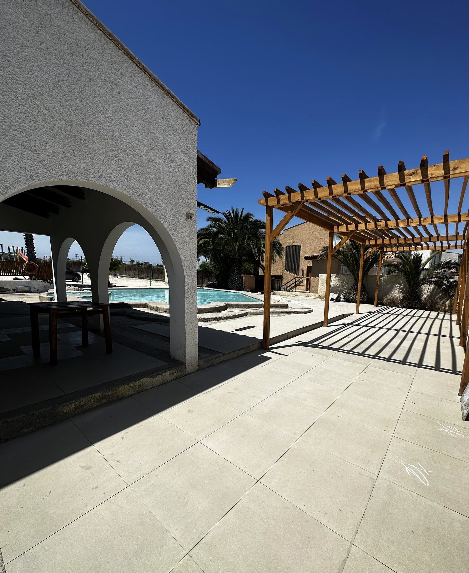 Terraza con pérgola de madera y piscina al fondo